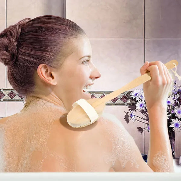Woman using long-handled bath brush for back exfoliation in tiled bathroom