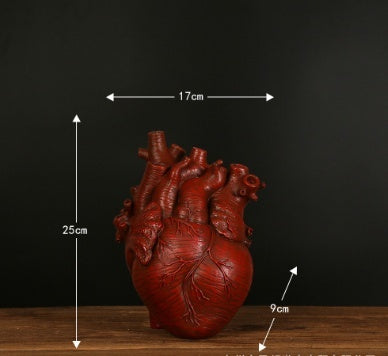 Realistic anatomical heart sculpture in red on wood table with measurements labeled