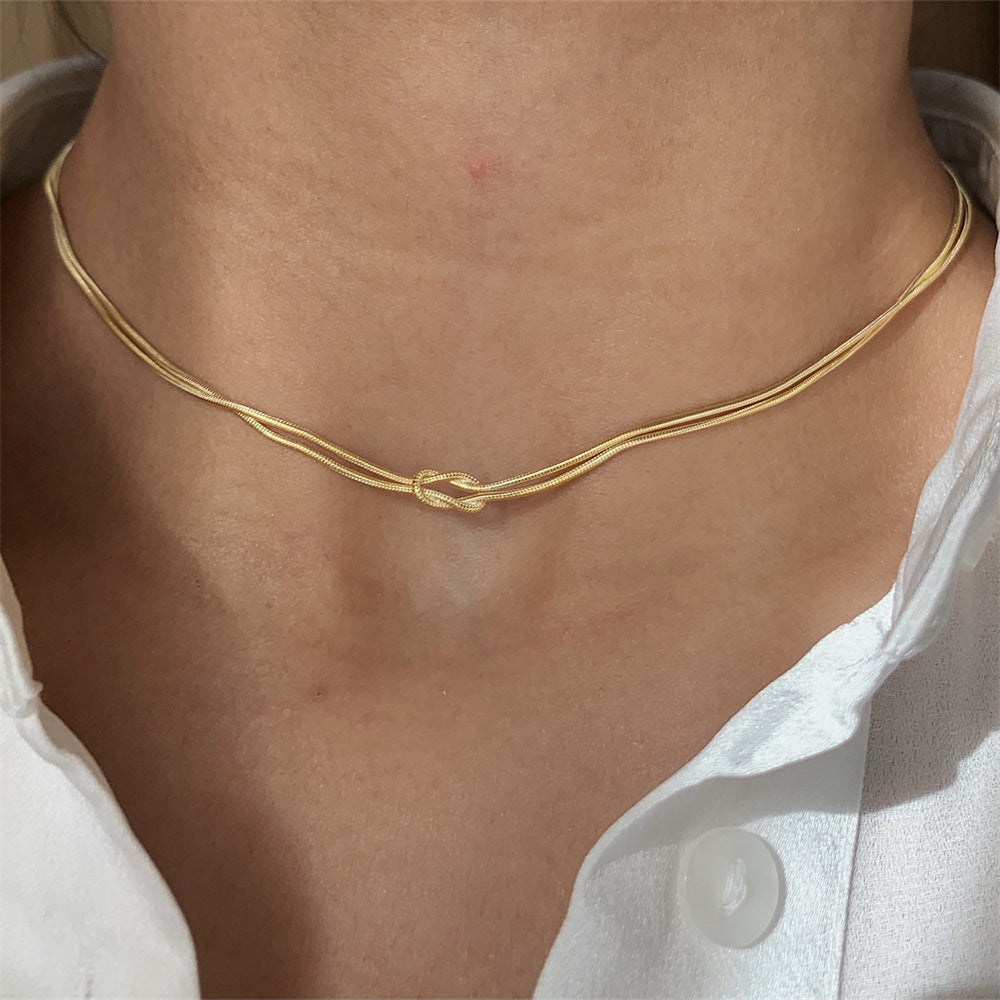 Gold knot choker necklace on neck, elegant minimalist jewelry close-up