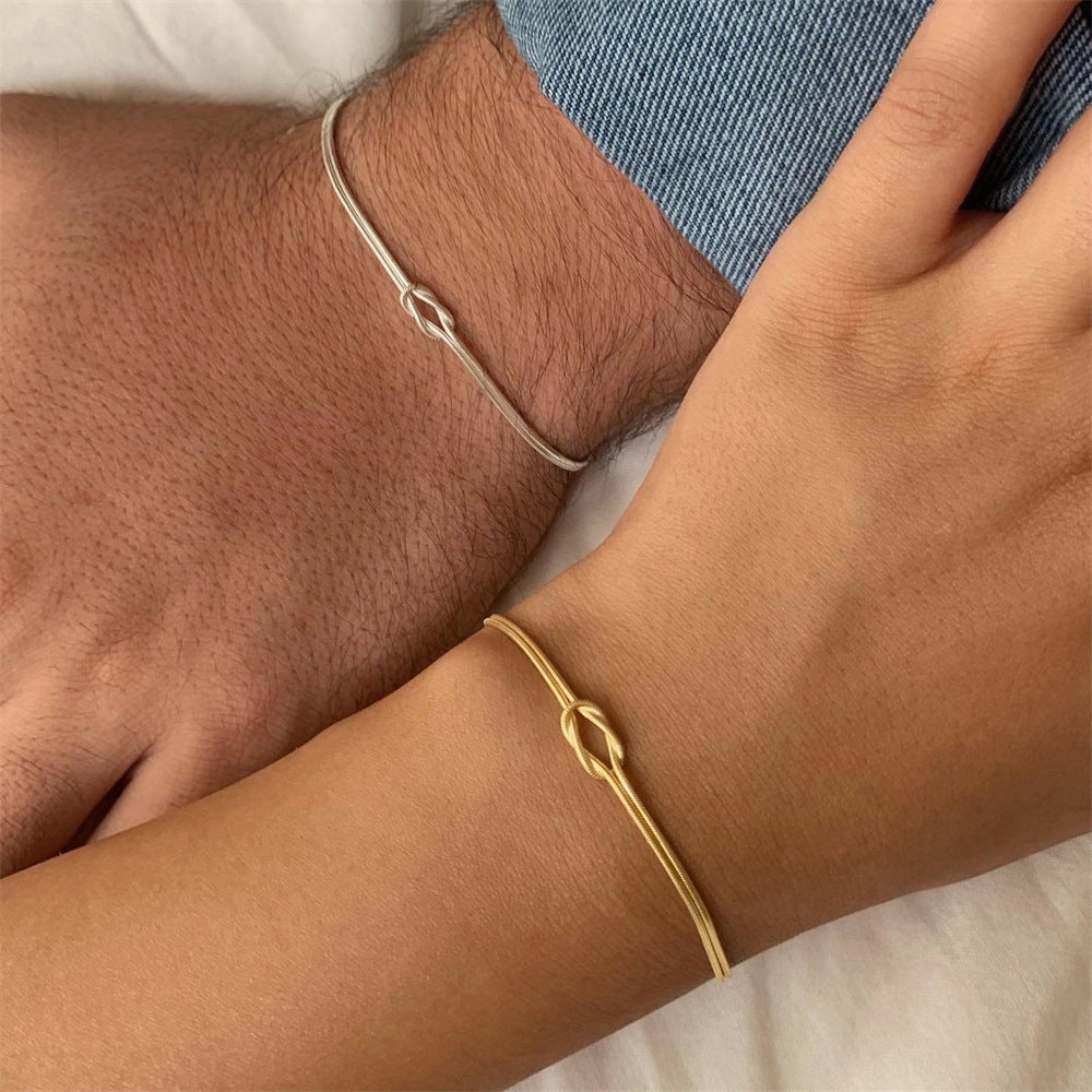 Minimalist gold and silver knot bracelets on two wrists, close-up jewelry shot